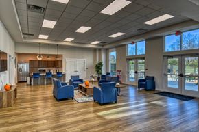 Indianapolis apartment for rent - A spacious waiting room with blue chairs and a wooden floor at The Landing Apartments, Indianapolis