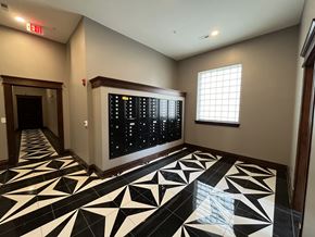 Crawfordsville apartment for rent - A hallway with a black and white tiled floor and a digital clock on the wall.
