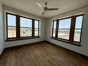 Crawfordsville apartment for rent - A room with wooden floors and two windows overlooking a parking lot.