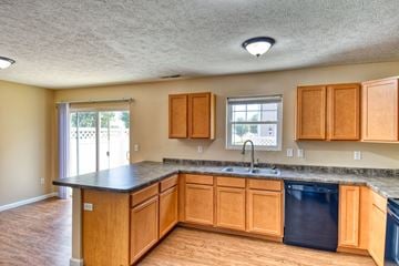 Terre Haute triplex for rent - A kitchen with wooden cabinets and black countertops.