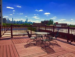 Chicago apartment for rent - A wooden deck with a table and chairs overlooking a city skyline.