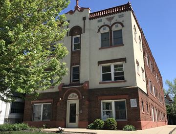 Cleveland apartment for rent - an old brick building with a white facade and a tree