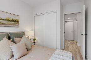 Ottawa apartment for rent - A bedroom with a bed, pillows, a lamp, and a painting on the wall.
