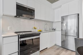 Ottawa apartment for rent - A modern kitchen with white cabinets and a stainless steel refrigerator.