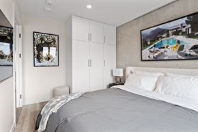 Ottawa apartment for rent - A bedroom with a large bed and a painting of a pool scene on the wall.