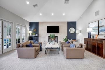 San Antonio apartment for rent - A living room with a grey carpet and a flat screen TV mounted on the wall.