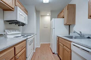 Grand Prairie apartment for rent - A kitchen with white appliances and wooden cabinets.