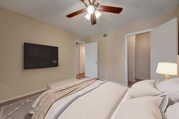Garland apartment for rent - A bedroom with a large bed and a flat screen TV mounted on the wall.