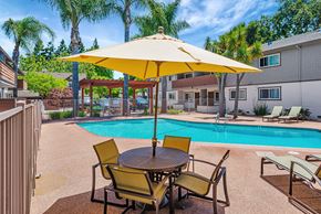 Menlo Park apartment for rent - A yellow umbrella shades a table with chairs around a pool.