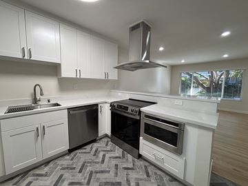 Palo Alto apartment for rent - A modern kitchen with white cabinets and a black stove top oven.