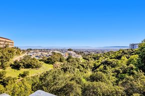 San Mateo apartment for rent - A view from a high vantage point overlooking a lush green landscape with buildings in the distance.