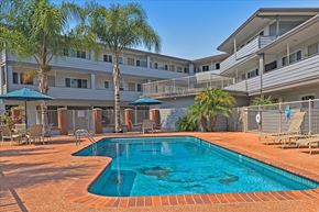 Menlo Park apartment for rent - A swimming pool surrounded by a patio with chairs and umbrellas.