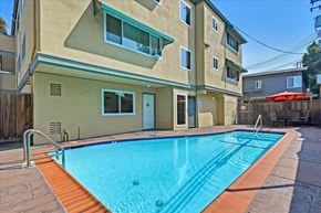 Redwood City apartment for rent - a swimming pool is in front of an apartment building with a pool