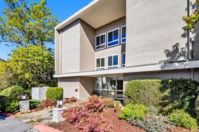 San Mateo apartment for rent - A modern building with a grey exterior and a red brick pathway leading to the front door.