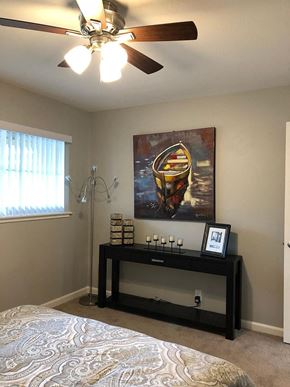 Sunnyvale apartment for rent - A bedroom with a bed, a ceiling fan, a painting, and a shelf with various items.