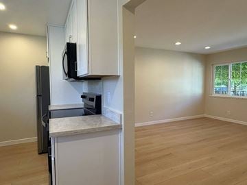 Palo Alto apartment for rent - A kitchen with white cabinets and a black microwave.