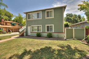 Menlo Park apartment for rent - A green house with a white door and windows is surrounded by a green lawn.