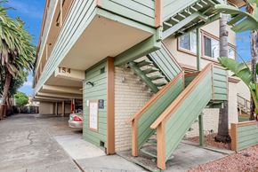 Redwood City apartment for rent - A green building with a staircase leading to the second floor.