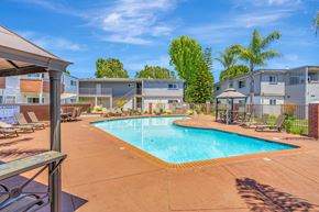 Sunnyvale apartment for rent - A swimming pool surrounded by a patio with chairs and a building in the background.
