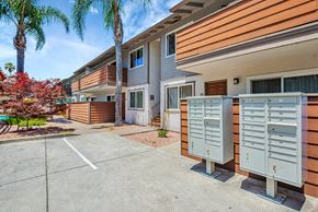 Menlo Park apartment for rent - A sunny day at a residential complex with a parking lot in the foreground.