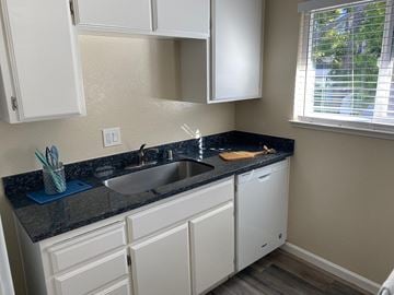 Sunnyvale apartment for rent - A kitchen with white cabinets and a black countertop.