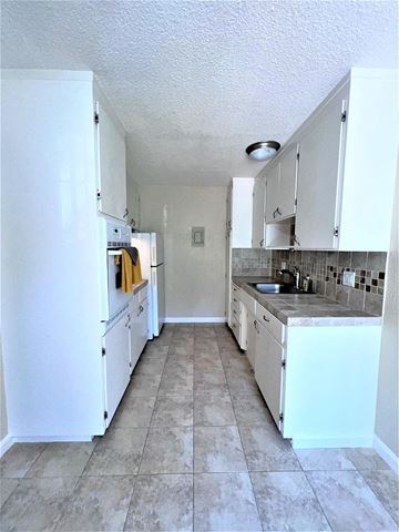 Sunnyvale apartment for rent - A kitchen with white cabinets and a white refrigerator.