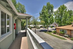 Menlo Park apartment for rent - A balcony with a railing overlooks a tree-lined street.