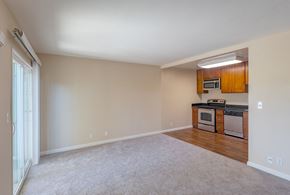 Palo Alto apartment for rent - an empty living room and kitchen with wood cabinets and white carpet