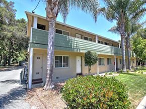 Menlo Park apartment for rent - A building with a green balcony and a white door is surrounded by trees.