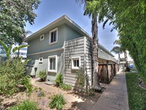 Sunnyvale apartment for rent - A building with a grey exterior and a brown door is surrounded by greenery.