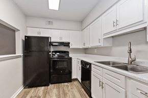 Kansas City apartment for rent - A kitchen with black appliances and white cabinets.