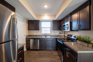 Comstock Park apartment for rent - A kitchen with dark wood cabinets and stainless steel appliances.