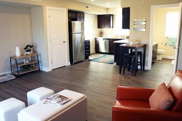 Caledonia apartment for rent - A living room with a red couch and a white ottoman.