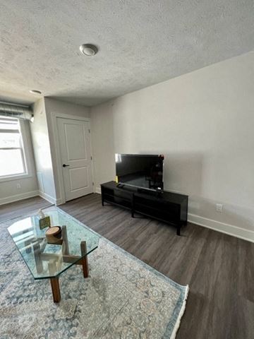 Grand Rapids apartment for rent - A living room with a glass coffee table and a black entertainment center.