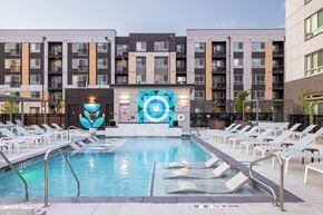 Arvada apartment for rent - A large pool surrounded by lounge chairs in front of a building.