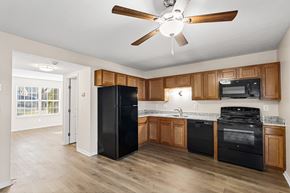 Erlanger triplex for rent - A kitchen with black appliances and wooden cabinets.