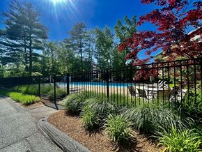Framingham apartment for rent - A pool surrounded by a black fence and red trees.