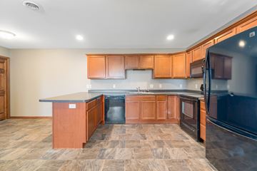 Menomonie apartment for rent - A kitchen with wooden cabinets and a black refrigerator.