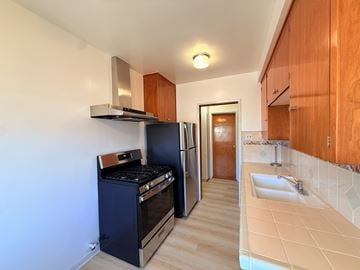 Los Angeles triplex for rent - A kitchen with a black oven and wooden cabinets.