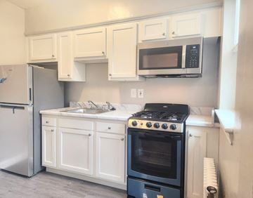 Washington apartment for rent - A kitchen with white cabinets and a black stove top oven.