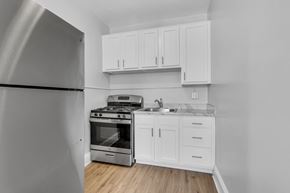 Washington apartment for rent - A kitchen with a stainless steel refrigerator, stove, and white cabinets.