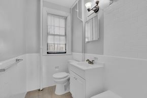 Washington apartment for rent - A white bathroom with a toilet, sink, and window.