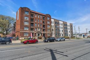 Washington apartment for rent - A red car is parked on the side of the road in front of a brick building.