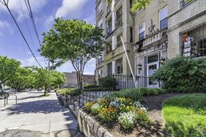 Washington apartment for rent - a sidewalk in front of a building with trees and flowers
