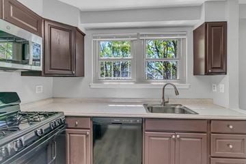 Washington apartment for rent - A kitchen with brown cabinets and a black stove top oven.