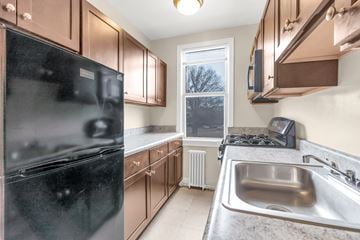 Washington apartment for rent - A kitchen with brown cabinets and a black fridge.
