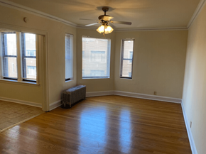 Chicago apartment for rent - an empty living room with a ceiling fan and three windows