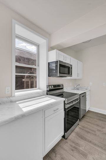 Washington apartment for rent - A kitchen with white cabinets and a black stove top oven.