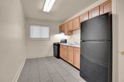 Hyattsville apartment for rent - A kitchen with a black refrigerator, wooden cabinets, and a window.