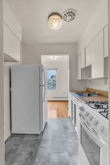 Silver Spring apartment for rent - A white kitchen with a large refrigerator and a stove top oven.
